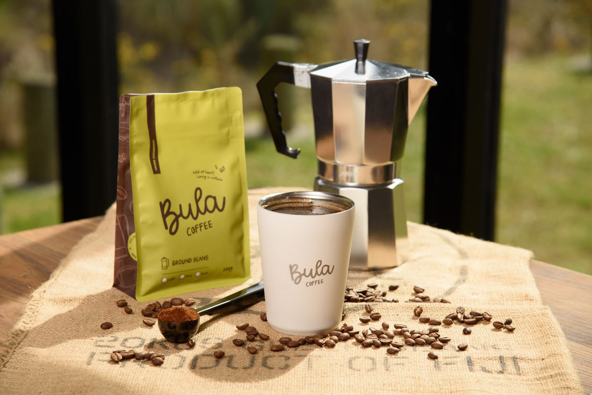 Bula Coffee ground beans with a white Bula to-go cup and a moka pot